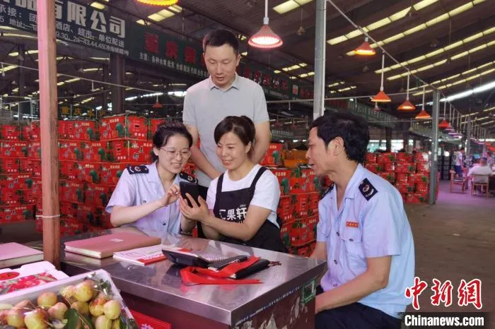 重庆市江津区税务人员辅导双福农贸城商户使用“农品慧”平台。　聂小淄 摄