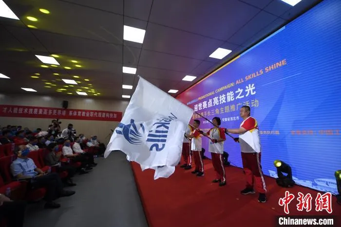 8名技能人才代表展示世界技能组织会旗和上海第46届世界技能大赛会旗 孙兴伟 摄
