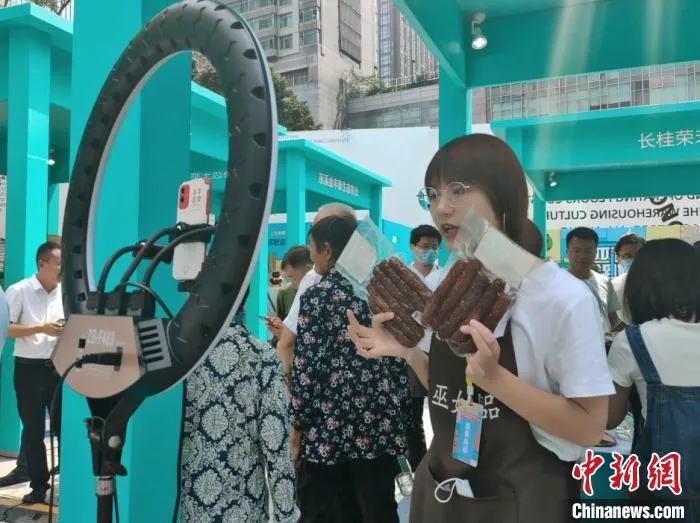 图为“巫姑腊味”展区工作人员正在直播。　袁子寒 摄