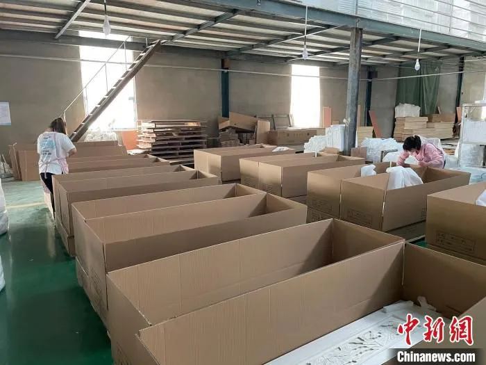 图为，庄寨镇一工厂工人正在打包棺木。　孙宏瑗 摄