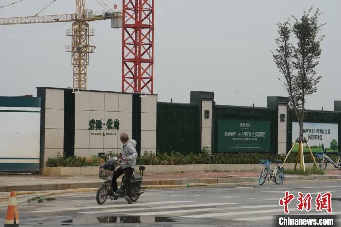 资料图：郑州北龙湖一市民路过在建楼盘。 董飞 摄 