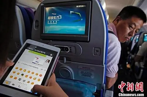  图为2014年7月23日，旅客在东航实际承运的航班上使用平板电脑(Pad)，进行空地互联微信聊天。 中新社记者 殷立勤 摄