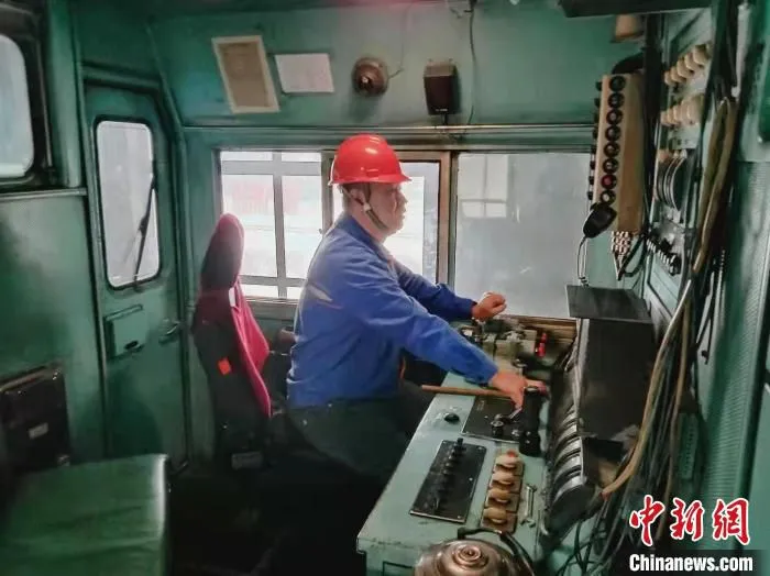 图为陈春彪坐在机车驾驶室内，聚精会神地检查每一个环节。　 张静 摄
