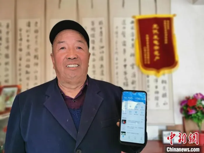 图为村民李生明展示自家光伏电站发电情况。　颜金梅 摄
