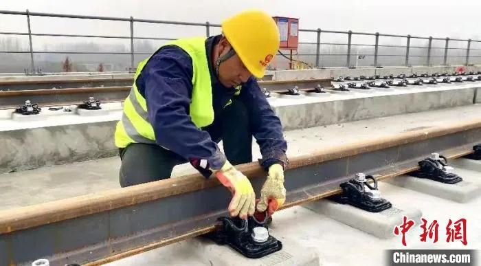 施工人员正在检查轨道的固定装置。　许无疾 摄