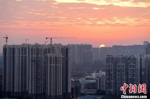 资料图：城区一角，太阳正从东方升起。中新社记者 刘忠俊 摄