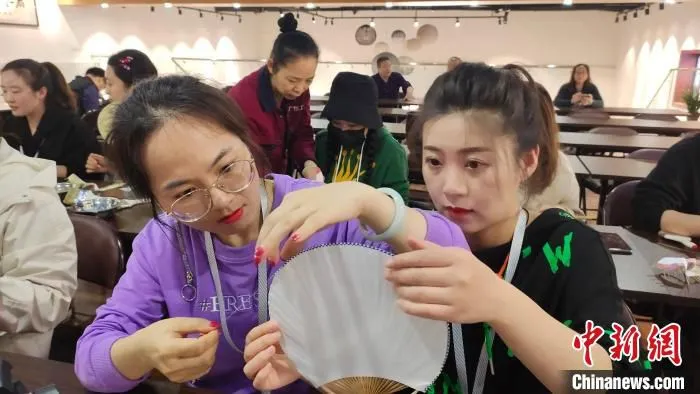 媒体记者们在体验学习团扇制作。?　杨宗盛 　摄