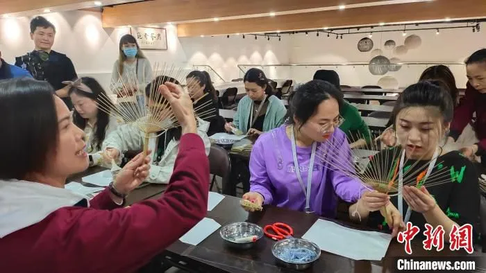 媒体记者们在体验学习团扇制作。?　杨宗盛 　摄