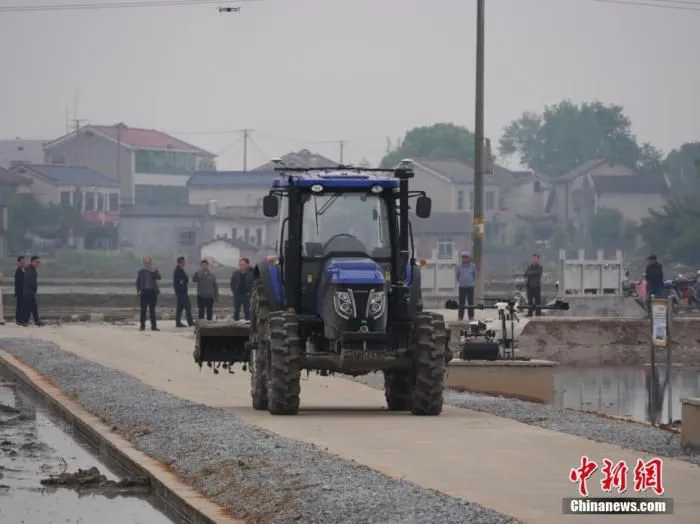 图为一辆旋耕机自动打火启动，缓慢行驶在路上。 中新社记者 王昊昊 摄