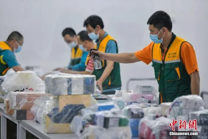 3月4日，在中国邮政集团公司海口市分公司离岛免税品邮寄送达处理中心，工作人员正在给即将邮寄的免税品进行消毒杀菌作业。据悉，海南离岛免税购物“邮寄送达”服务启动已“满月”。
中新社记者 骆云飞 摄