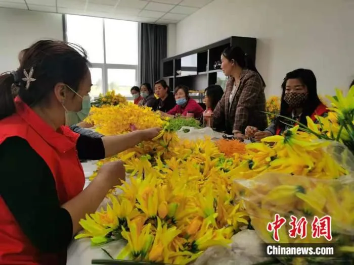 大同市云州区坊城新村黄花产业园内，二十余名妇女围坐在长桌前，埋头制作“黄花”绢花。高雨晴 摄