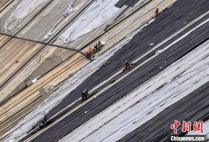 施工人员正在上库大坝坝面进行保温材料覆盖作业(资料图) 沈志华 摄