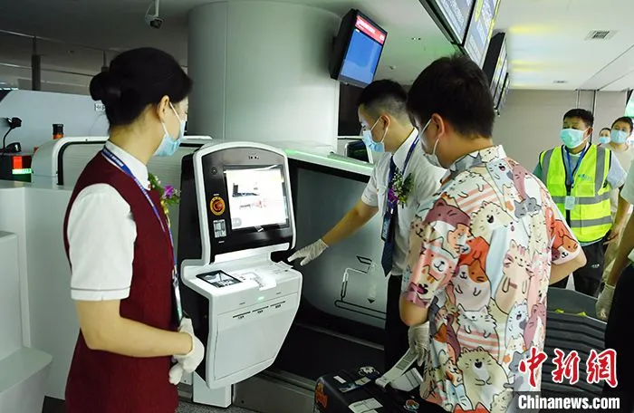 6月27日，四川成都，工作人员协助旅客通过自助系统办理登机手续和行李托运。当日，四川航空公司3U8001航班搭载着262名乘客从成都天府国际机场飞往北京首都国际机场，这是天府机场正式启用后的首飞商业航班，标志着中国“十三五”期间规划建设的最大民用运输机场项目正式通航投运。 中新社记者 刘忠俊 摄 