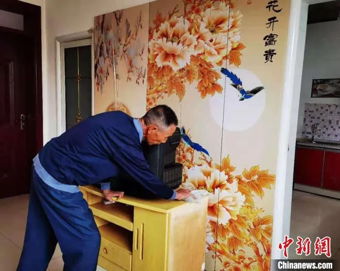 图为村民陈同林每天的日常生活，拿着抹布擦拭新家的桌子，打扫地板，再擦擦厕所的水箱。　史静静 摄