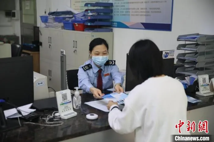图为江门高新区税务人员向缴费人派发社保费缓交宣传小册子 杨伟 摄
