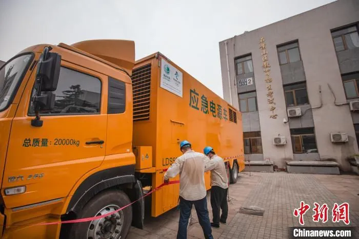 图为国网北京石景山供电公司发电车运行人员在区考试中心开展发电车接入工作。　李强 摄