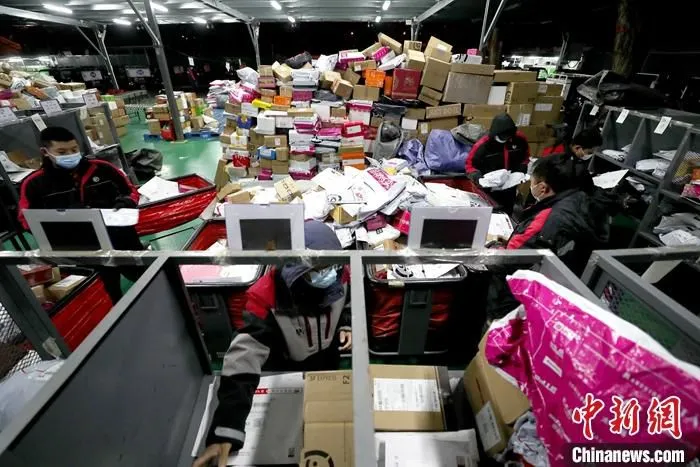 资料图为北京一快递站内，快递员分捡快递。 中新社记者 张宇 摄 　