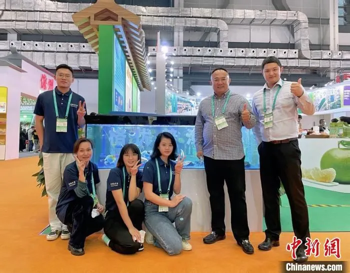 洪小贺与父亲及工作人员在海水观赏鱼展台前合影。　符宇群 摄