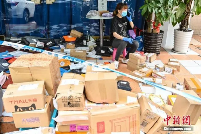 6月3日，广东省广州市海珠区瑞宝街南洲名苑小区，工作人员在小区门外无接触配送区域整理居民的快递。6月2日凌晨，广州市卫健委发布通告称，海珠区瑞宝街南洲名苑棠阁(A栋、B栋、C栋)由低风险地区调整为中风险地区。根据防控要求，小区居民原则上足不出户，只进不出。 中新社记者 陈骥旻 摄