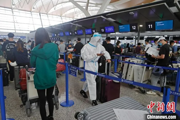 旅客身穿隔离服排队等待办理登机手续。　殷立勤 摄
