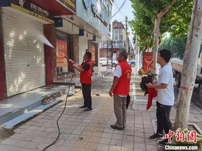志愿者正在清洗商铺门面。　郝晓东 摄