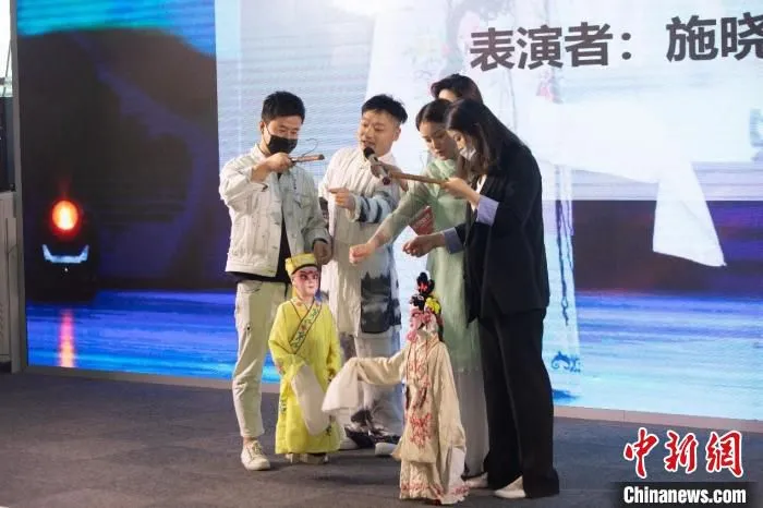 有幸运观众被邀请到舞台上，跟着两位年轻的木偶昆曲表演者学习。　吴江区供图