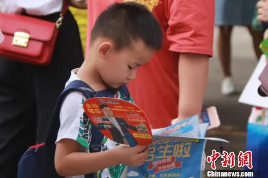 刚从学校出来的学生正在整理他接到的传单。　罗鹏 摄