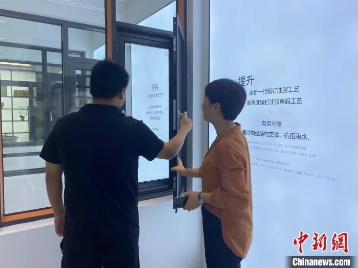 佛山市欧轩门窗有限公司总经理王莹(右)向采购商介绍产品创意设计。　邓志洋 摄