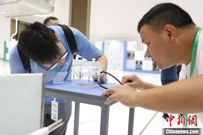 工作人员通过小实验展示气凝胶材料的透气性能。　王洁 摄