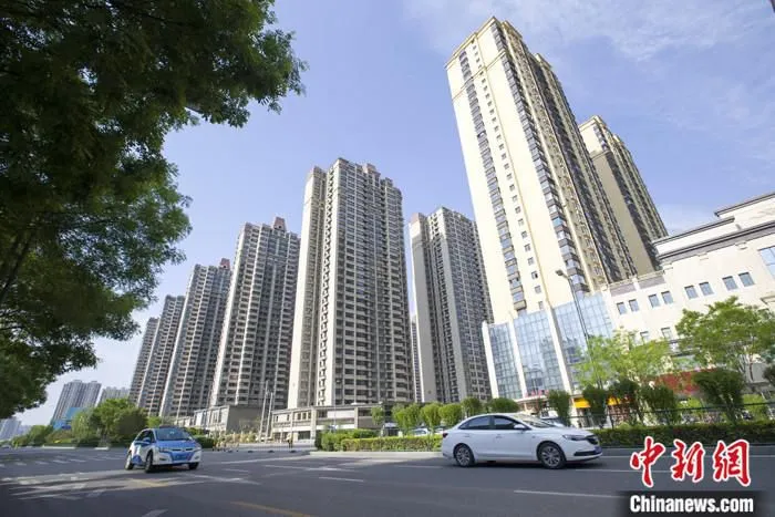 资料图：车辆从一楼盘前经过。 中新社记者 张云 摄