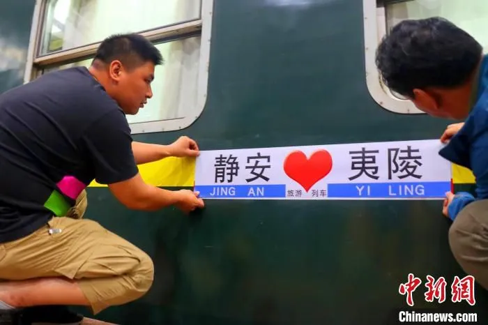 工作人员为“静安·夷陵号”旅游专列贴上车牌。　李重庆 摄