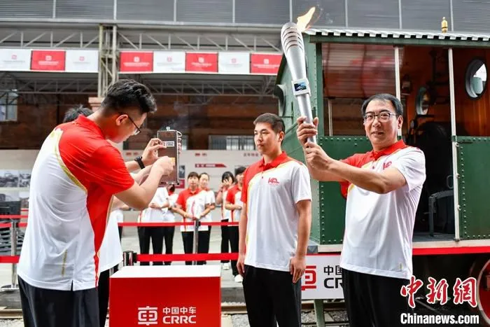 图为中国中车集团党委书记、董事长孙永才(右)高举火炬。该火炬将在中国中车境内各企业、境外主要生产制造基地接续传递。 中新社发 赵亮 摄