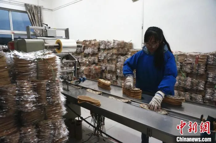 图为龙门村生产车间内，一名女工正在对鞋垫进行包装。　韩章云 摄