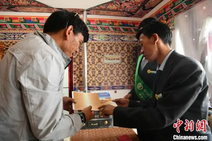 图为农行日土县支行工作人员为村民宣讲贷款政策。　贡嘎来松 摄