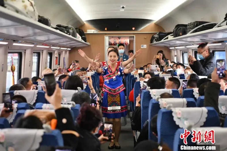 2021年12月3日，连接中国昆明和老挝首都万象、全线采用中国标准的中老铁路全线开通运营。图为身着民族服饰的列车员为旅客带来特色节目。中新社记者 刘冉阳 摄
