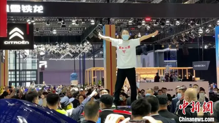 一位身穿“刹车失灵”字样衣服的女士站在一辆特斯拉展车车顶 康玉湛 摄