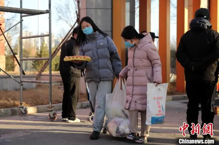 图为12月29日，西安市北郊一小区内，居民领取蔬菜等物资。　张远 摄