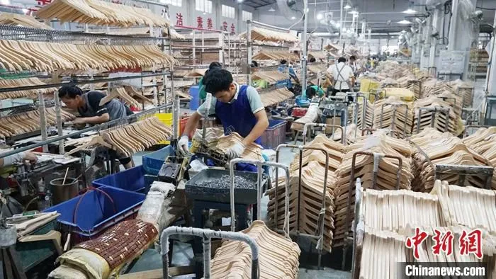 广西荔浦被誉为“中国衣架之都”，2020年衣架家居产业产值近20亿元人民币，其中80���出口欧美、东南亚等国家和地区。资料图为工人在组装衣架。 中新社发 欧惠兰 摄