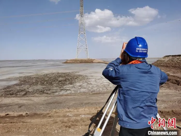 图为“电力天路”青藏联网工程运维人员观测线路基础沉降情况。　李杰 摄