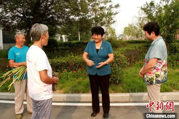 图为高淑贞在三涧溪村与村民交谈。　受访者供图