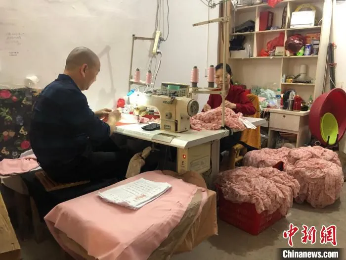 思源社区居民杨流生夫妇在车库改造的“扶贫车间”里赶制服装 阮煜琳 摄
