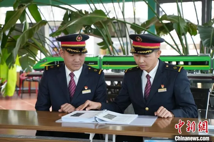 图为李光登(左)与同事阅读专业技术书籍。　许津铭 摄