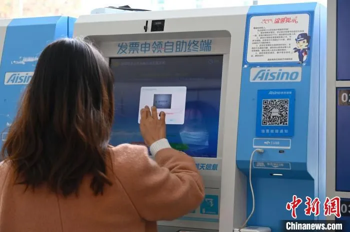 图为一名企业财务人员通过发票申领自助终端申领发票。