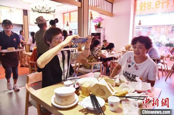 图为在店内用餐的顾客用手机拍摄小吃。 许琰 摄 图为在店内用餐的顾客用手机拍摄小吃。 许琰 摄