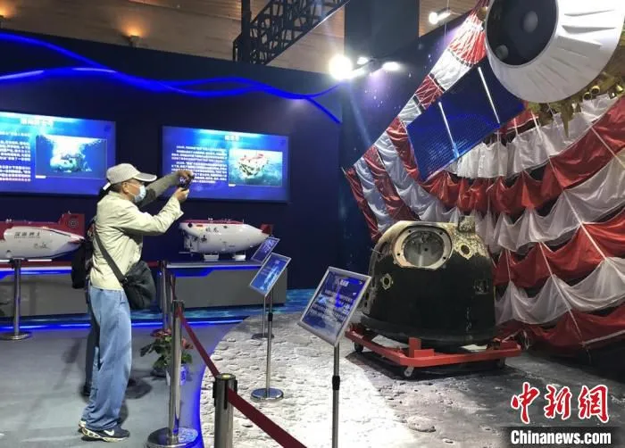 市民拿出手机拍摄成果展中展出的实物及模型。　孙权 摄