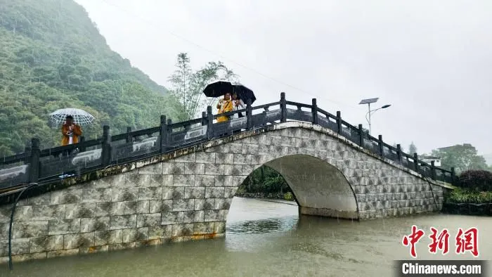 采访团记者在岚岩村冒着大雨相互拍照。　杨宗盛 　摄