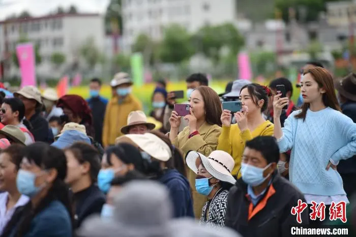 图为西藏自治区拉萨市墨竹工卡县小油菜花文化旅游节现场游客拿出手机拍摄节目。　贡嘎来松 摄