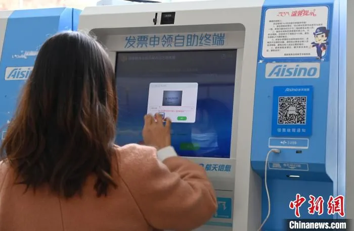 图为一名公司财务人员通过发票申领自助终端领取发票。