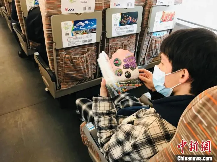 图为旅客观看《鄂尔多斯四季赏花文旅活动》宣传册。　刘奇 摄