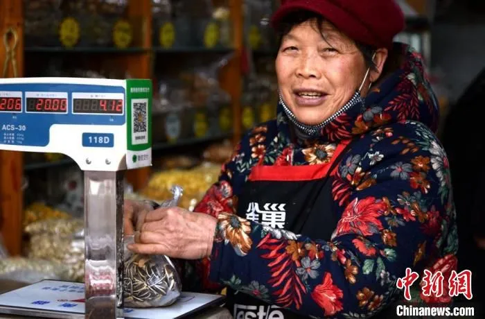 春节前夕，徐州市内一邳州炒货店内，韩大娘把瓜子称重为顾客打包。(资料图) 朱志庚 摄